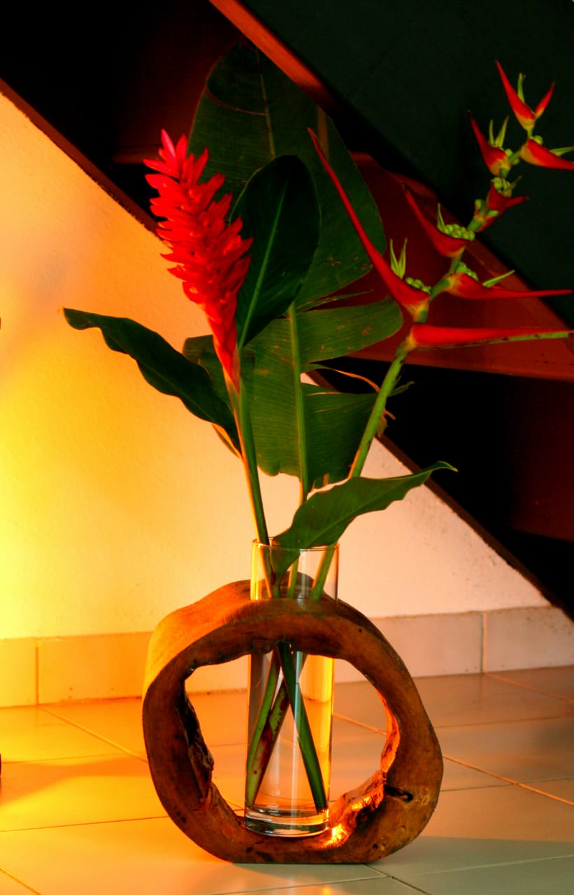 Vase artisanal avec des fleurs sous un escalier