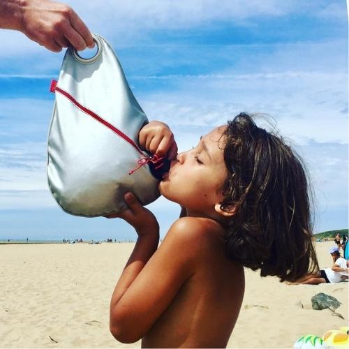 Enfant à la plage buvant à partir de la fontaine à boisson Obag'