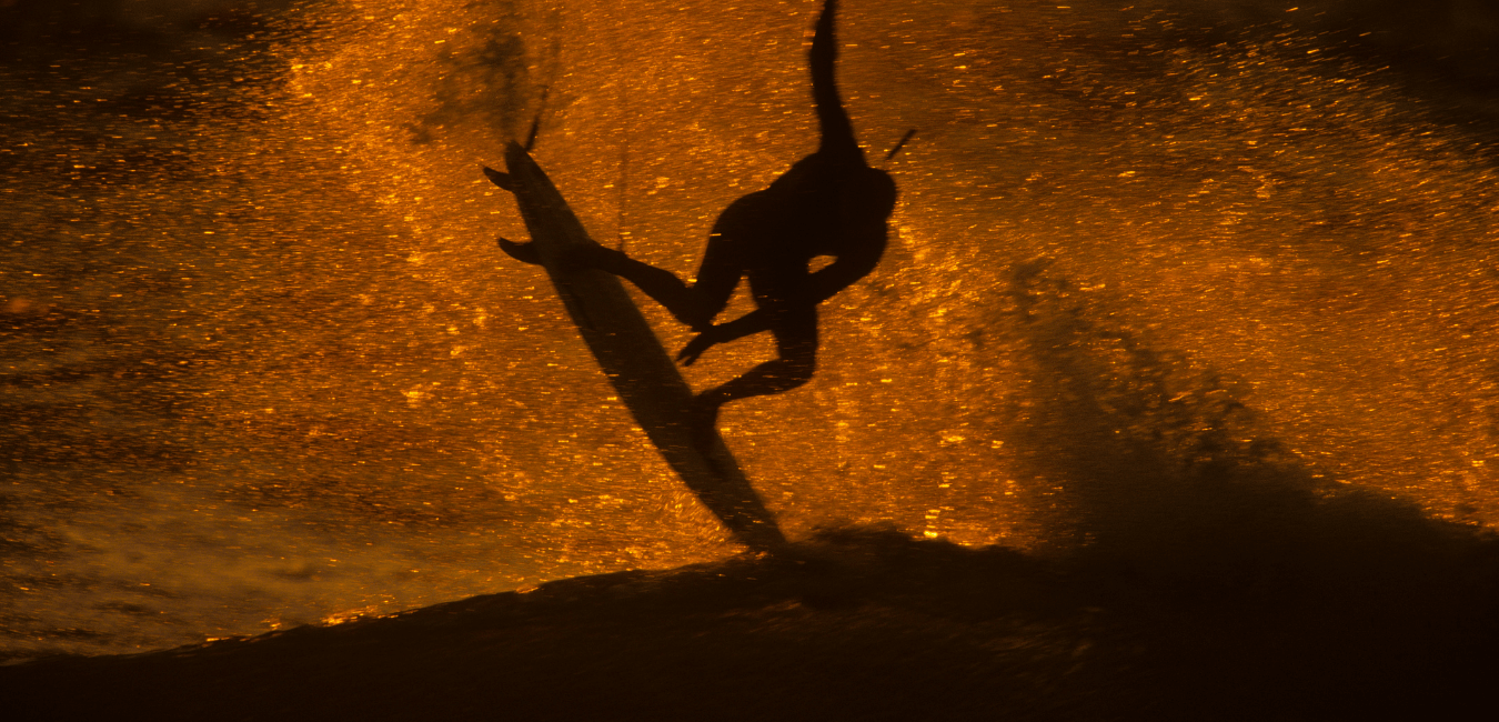 surfeur en train de réaliser un aerial au coucher du soleil