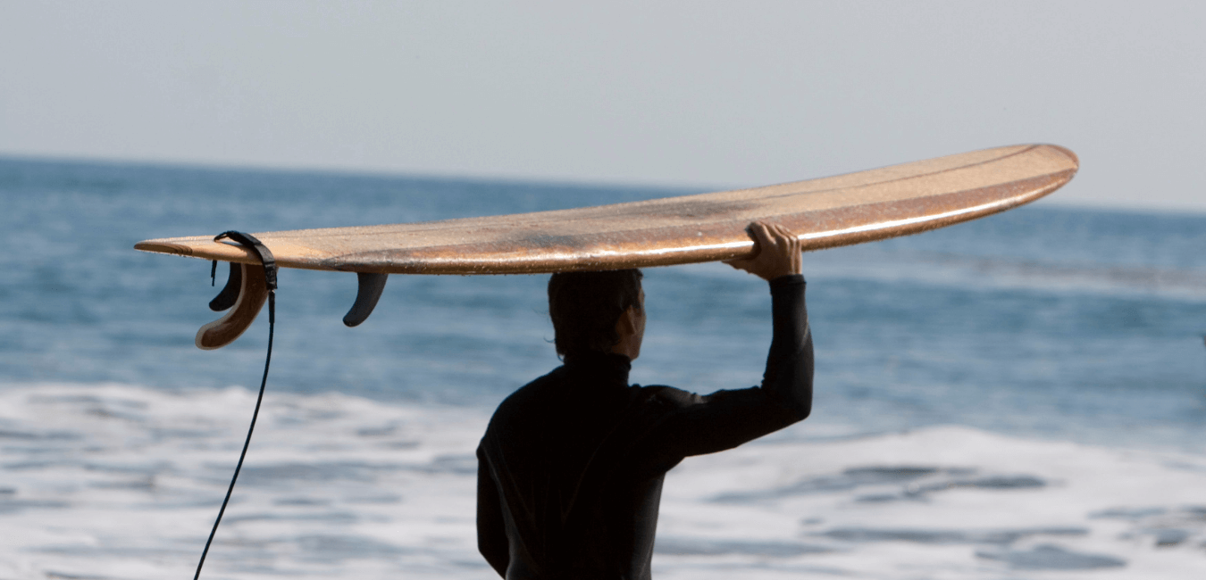 surfeur portant un longboard sur la tête