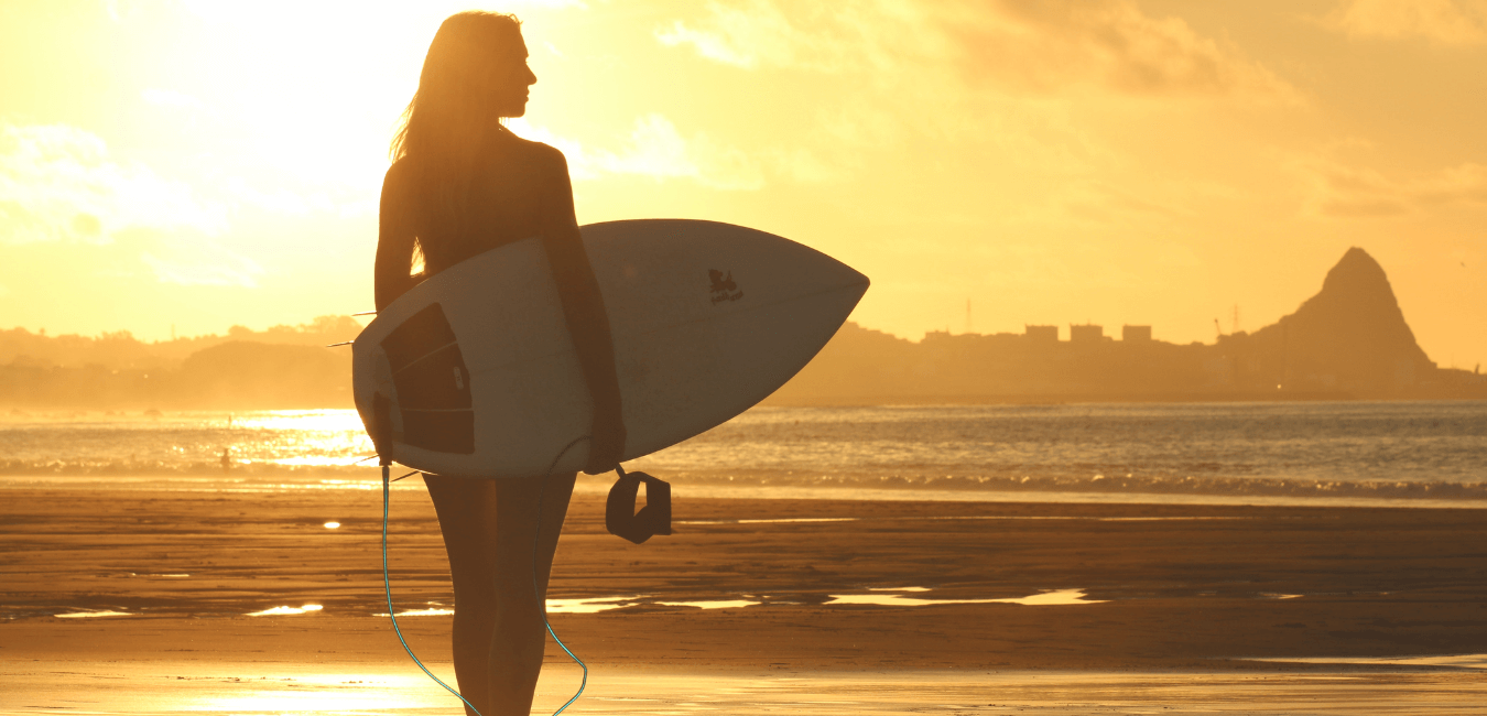 surfeuse avec sa planche au coucher de soleil