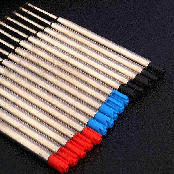 Recharges de stylo bille de différentes couleurs posé sur un carnet brun et sur un support noir