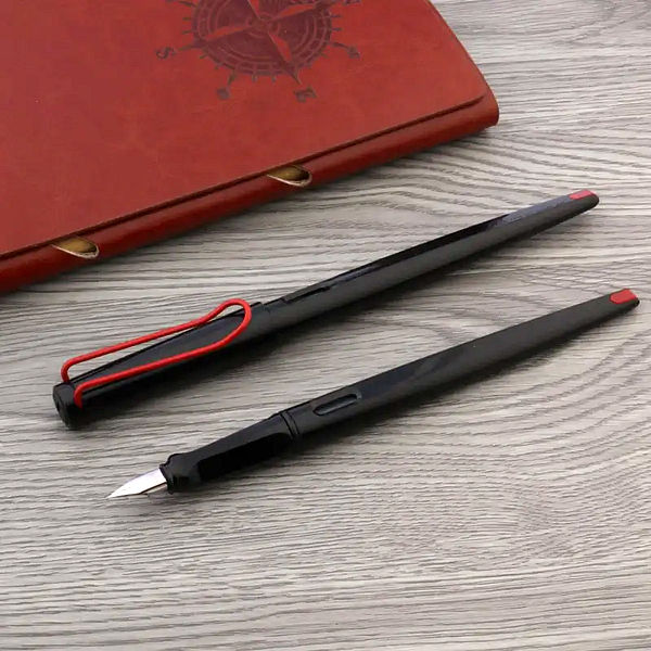 Un stylo plume long noir et rouge sur un support en bois à côté d'un carnet brun