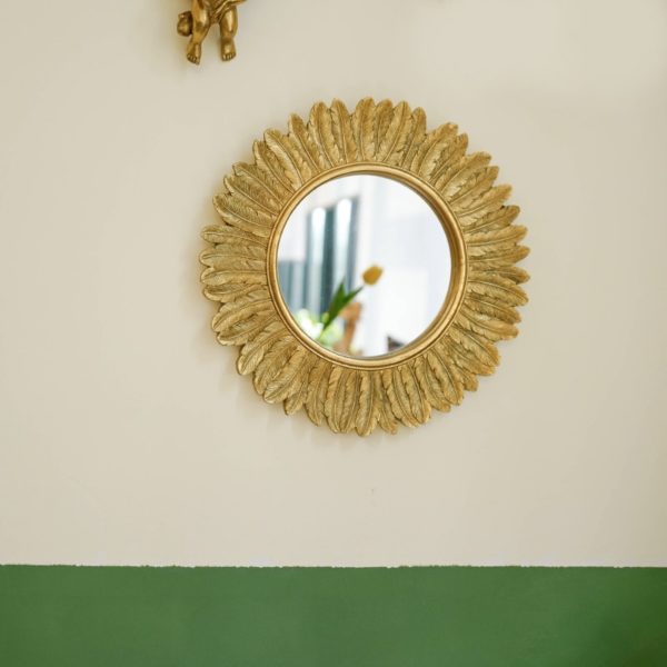 Miroir soleil Plume d'or vintage accroché au mur