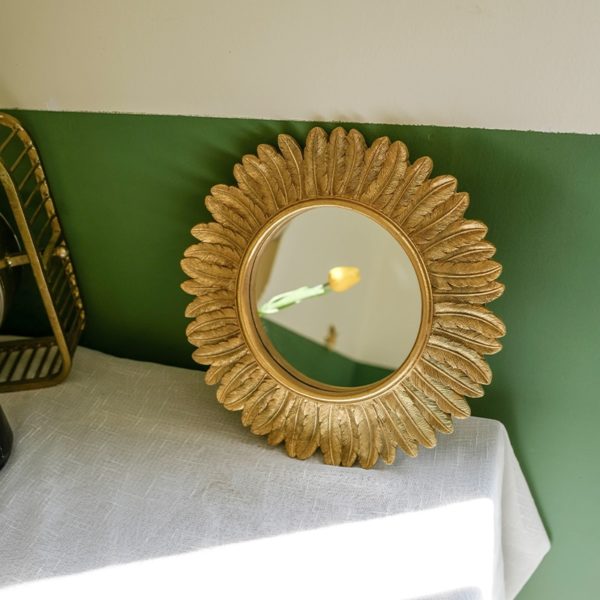 Miroir soleil Plume d'or sur une table vintage